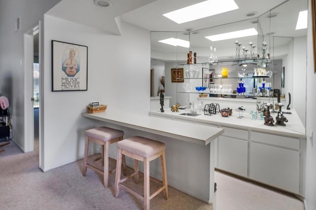 bar with white cabinets, sink, and light carpet