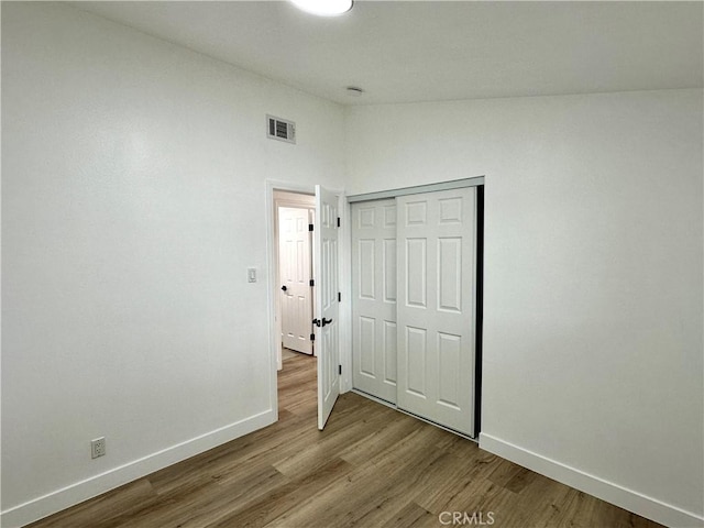 unfurnished bedroom with a closet, high vaulted ceiling, and wood-type flooring