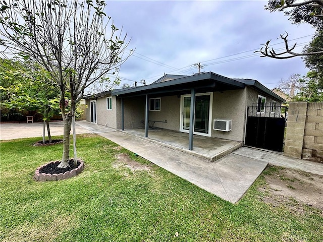 rear view of house featuring a lawn, a patio, and a wall unit AC