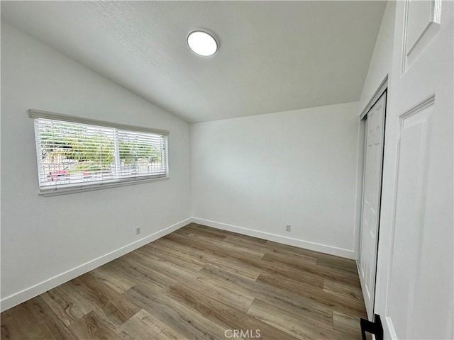 unfurnished bedroom with a closet, vaulted ceiling, and hardwood / wood-style flooring