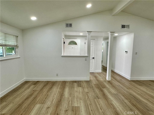 unfurnished room with vaulted ceiling with beams and light wood-type flooring