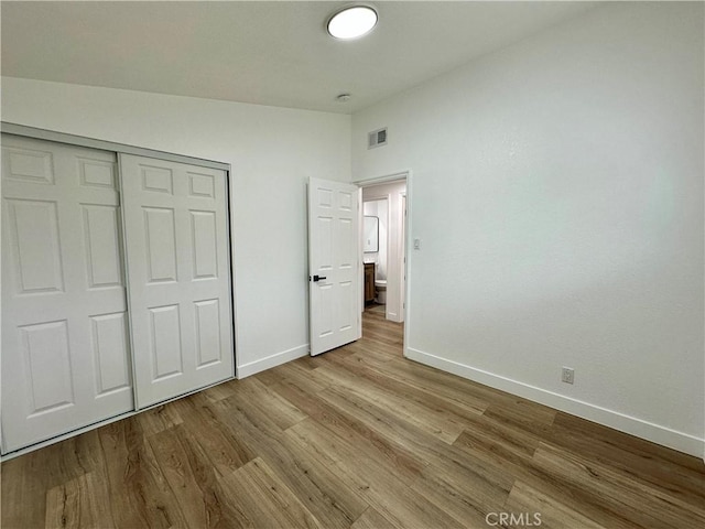 unfurnished bedroom featuring vaulted ceiling, light hardwood / wood-style flooring, and a closet