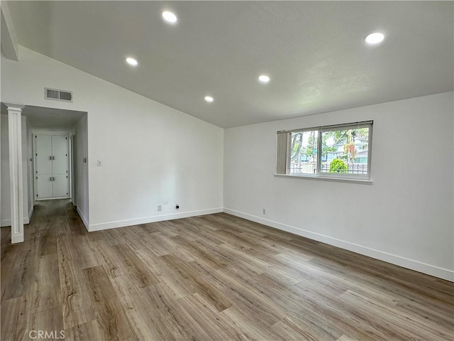 unfurnished room featuring light wood-type flooring and vaulted ceiling