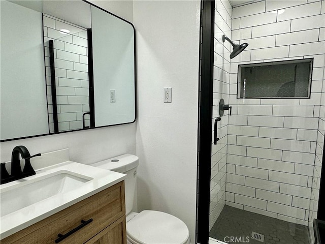 bathroom featuring a tile shower, vanity, and toilet