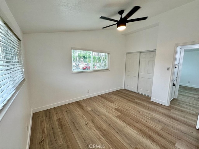 unfurnished bedroom featuring light wood-type flooring, a closet, vaulted ceiling, and ceiling fan