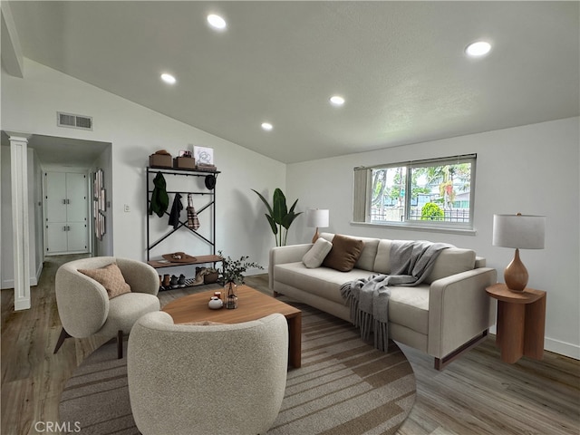 living room with hardwood / wood-style flooring, lofted ceiling, and decorative columns