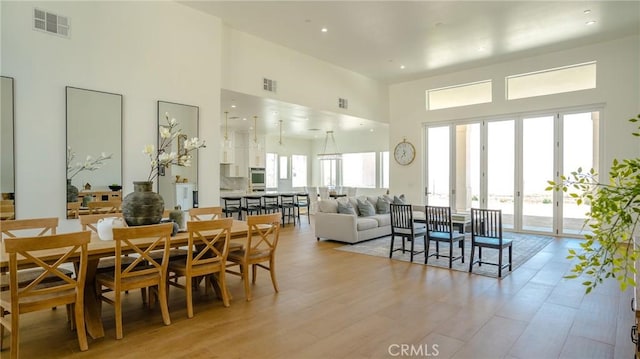 dining area featuring a towering ceiling and light hardwood / wood-style floors