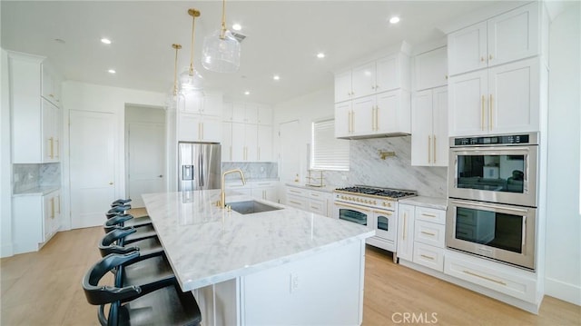 kitchen featuring white cabinets, sink, an island with sink, and stainless steel appliances