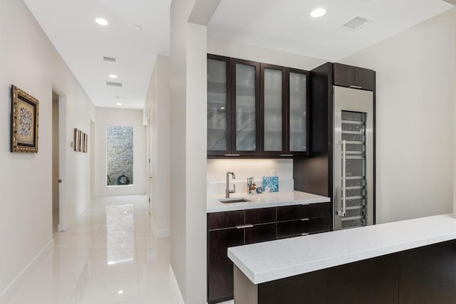 bar featuring dark brown cabinetry, wine cooler, and sink