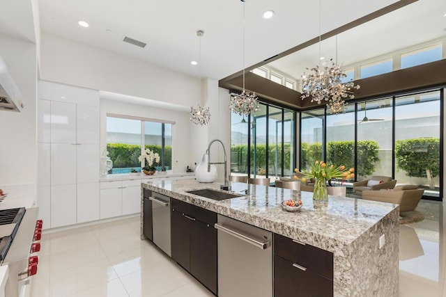 kitchen featuring sink, decorative light fixtures, an island with sink, a notable chandelier, and dark brown cabinetry