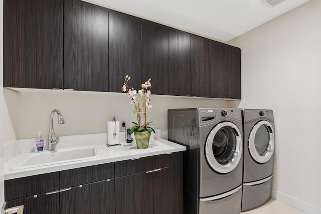 clothes washing area with cabinets, sink, and washing machine and clothes dryer