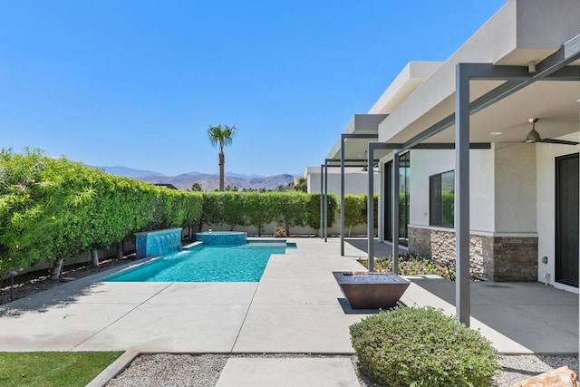 view of pool with a patio area, a mountain view, ceiling fan, and pool water feature