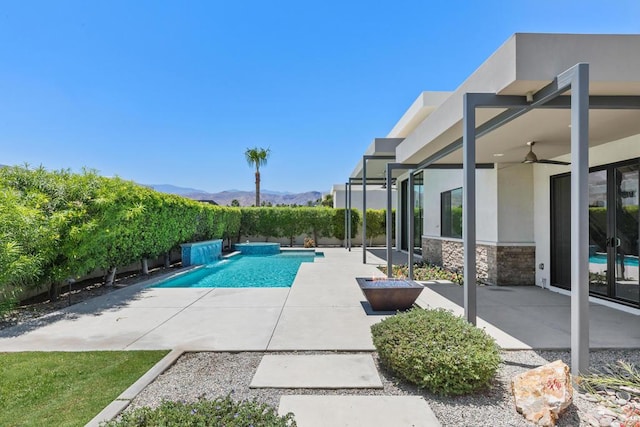 view of swimming pool featuring a mountain view, a patio, pool water feature, and ceiling fan