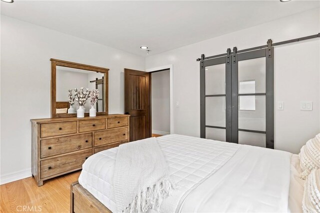 bedroom with a barn door and light hardwood / wood-style flooring