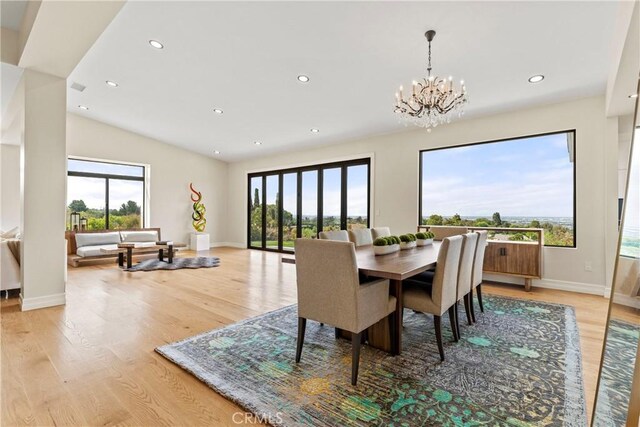 dining area with vaulted ceiling, a chandelier, a healthy amount of sunlight, and light hardwood / wood-style floors