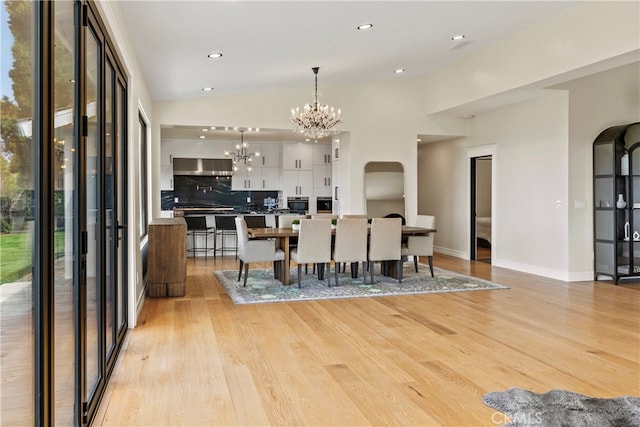 dining room featuring high vaulted ceiling, light wood-type flooring, and an inviting chandelier