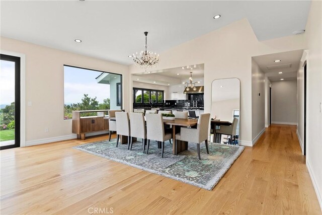 dining area featuring lofted ceiling, a chandelier, and light hardwood / wood-style floors