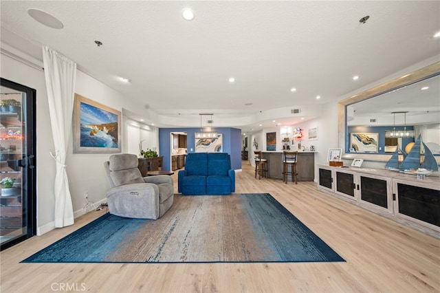 living room featuring light wood finished floors, recessed lighting, visible vents, bar, and baseboards