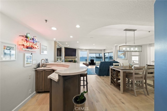 kitchen with decorative light fixtures, light countertops, light wood-style flooring, open floor plan, and baseboards