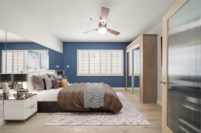 bedroom featuring a ceiling fan, light wood-style flooring, and baseboards