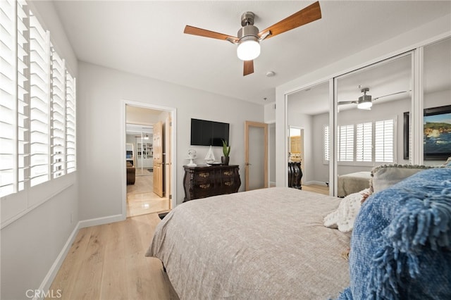 bedroom with light wood-type flooring, ceiling fan, baseboards, and a closet