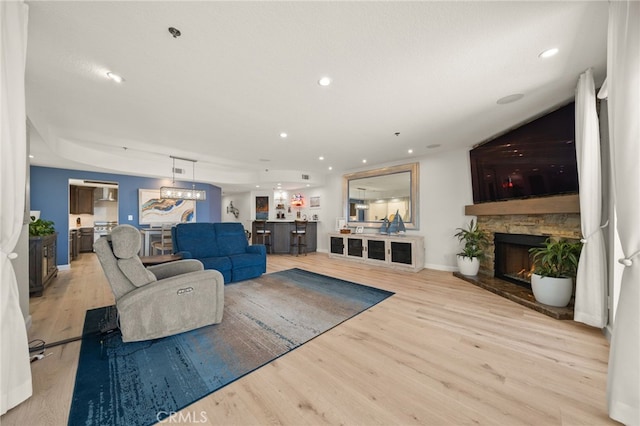 living room with light hardwood / wood-style flooring and a stone fireplace