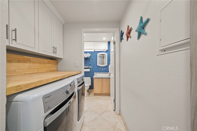 washroom featuring washer and clothes dryer, light tile patterned flooring, and cabinets