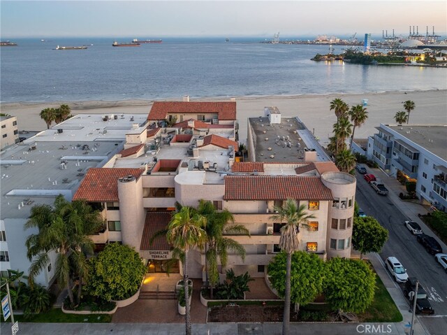 aerial view at dusk featuring a water view and a view of the beach