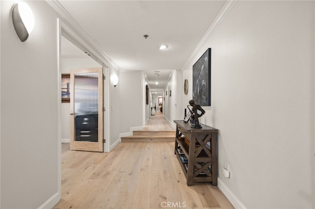 corridor featuring ornamental molding, light wood-type flooring, and baseboards