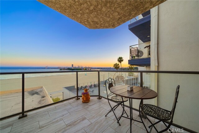 balcony at dusk featuring a water view