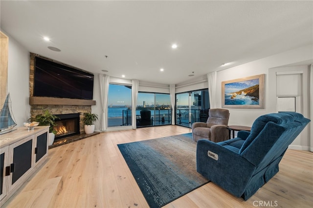 living room featuring light wood-style floors, recessed lighting, and a stone fireplace