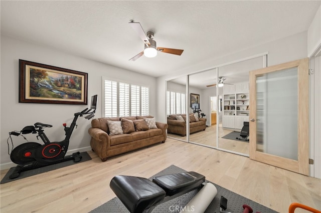 exercise area with ceiling fan, light wood-type flooring, a textured ceiling, and french doors