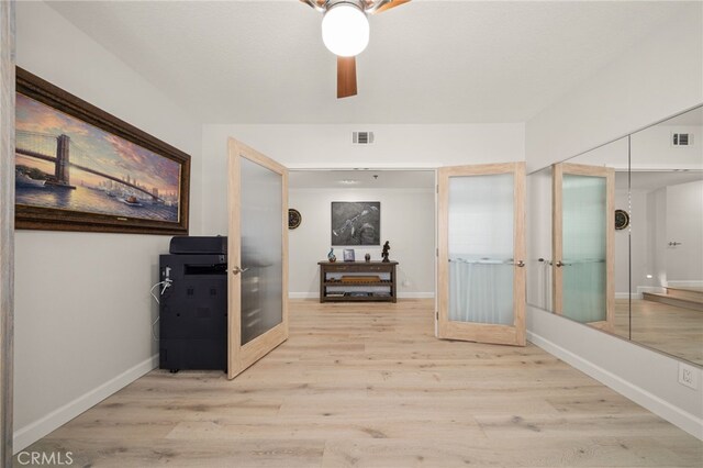 corridor with light hardwood / wood-style flooring and french doors