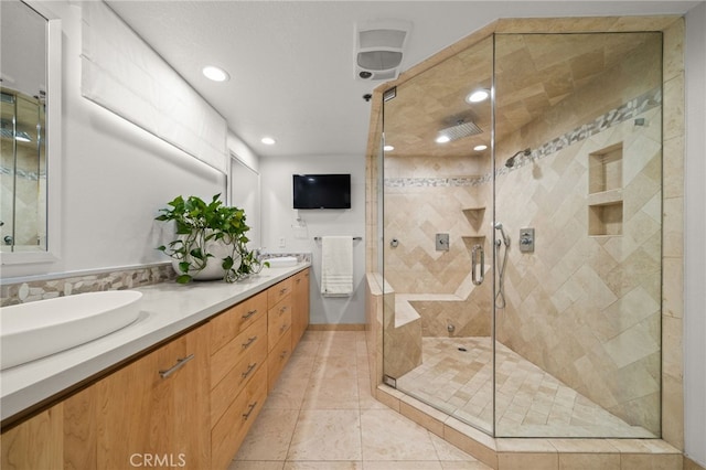 bathroom with tile patterned flooring, vanity, and a tile shower