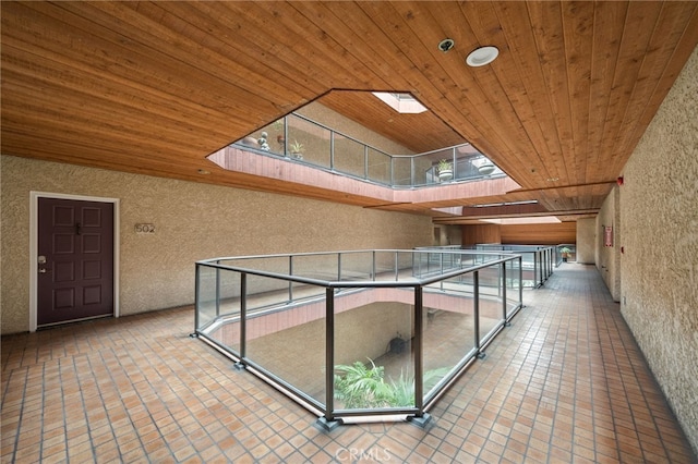 hall with a skylight, plenty of natural light, and wooden ceiling