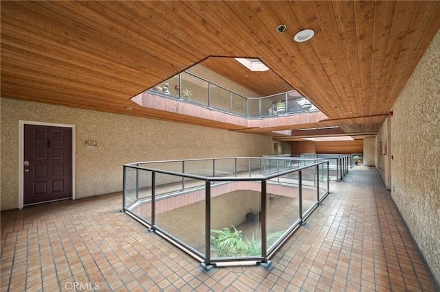 interior space with a skylight, wood ceiling, and tile patterned floors