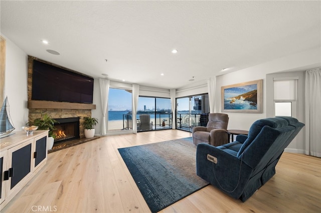 living area featuring light wood-style floors, a fireplace, and a textured ceiling