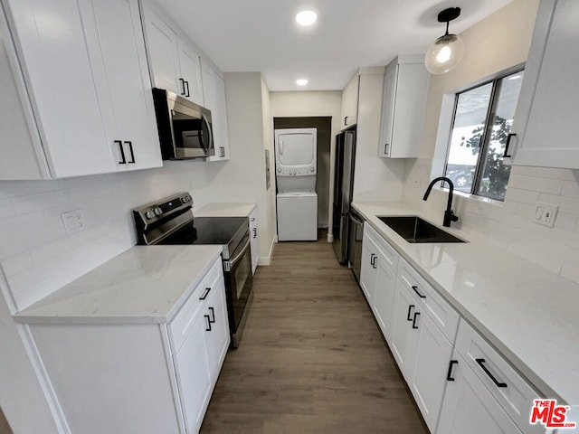 kitchen featuring sink, white cabinets, stacked washing maching and dryer, and appliances with stainless steel finishes