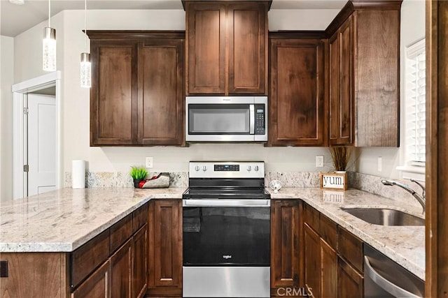 kitchen featuring kitchen peninsula, stainless steel appliances, hanging light fixtures, light stone countertops, and sink