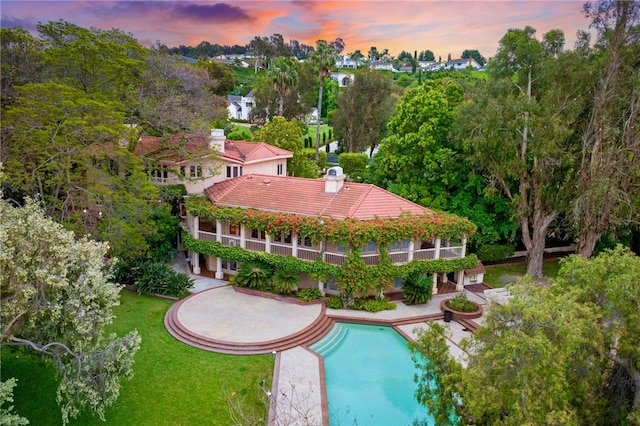 pool at dusk with a lawn and a patio area