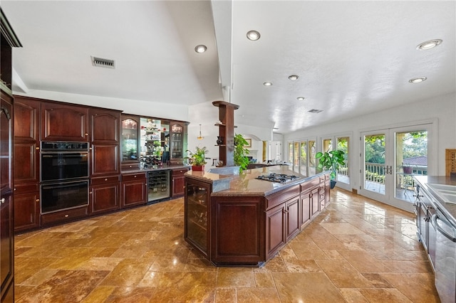 kitchen featuring lofted ceiling, a kitchen island, french doors, black double oven, and beverage cooler