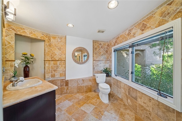 bathroom featuring toilet, tile walls, and vanity