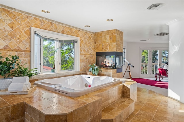 bathroom featuring a tiled fireplace and a relaxing tiled tub