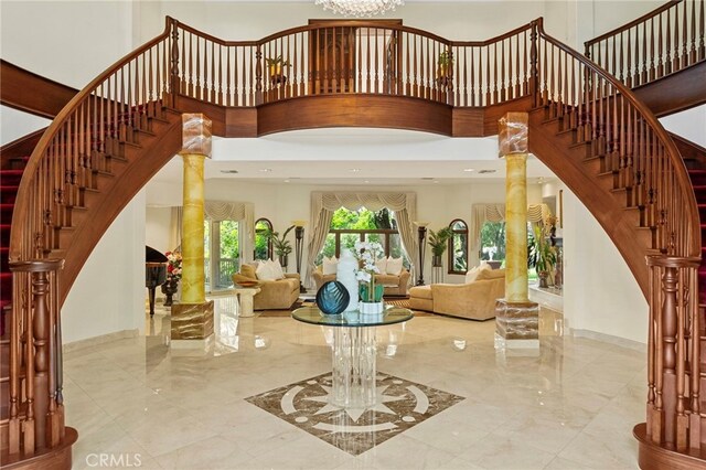 foyer with a towering ceiling, an inviting chandelier, and decorative columns