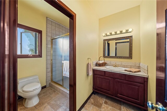 bathroom featuring a shower with shower door, vanity, and toilet