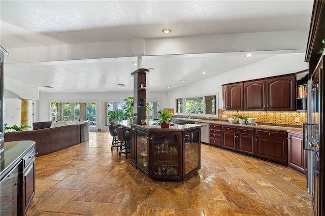 kitchen featuring lofted ceiling, a kitchen island, backsplash, stainless steel dishwasher, and dark brown cabinets