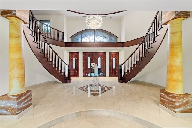 entrance foyer featuring a high ceiling, ornate columns, and an inviting chandelier