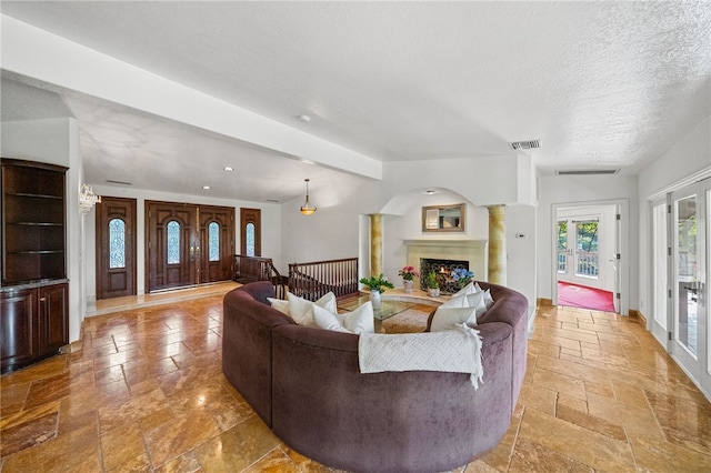 living room featuring beamed ceiling, a textured ceiling, and ornate columns