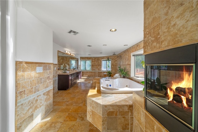 bathroom with tiled bath, tile walls, and vanity