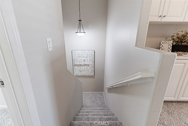 stairway featuring light colored carpet